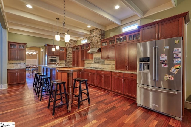 kitchen featuring under cabinet range hood, decorative backsplash, appliances with stainless steel finishes, and dark wood finished floors