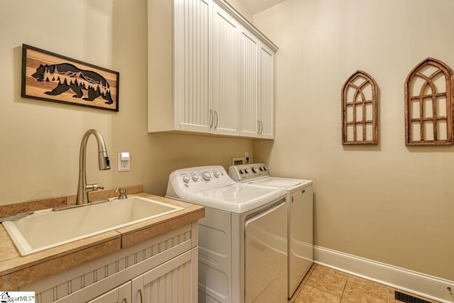 laundry area featuring washer and clothes dryer, a sink, cabinet space, light tile patterned flooring, and baseboards