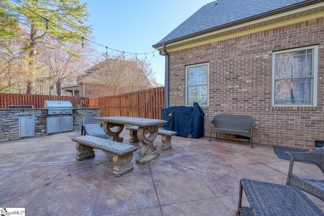 view of patio with area for grilling, an outdoor kitchen, and fence