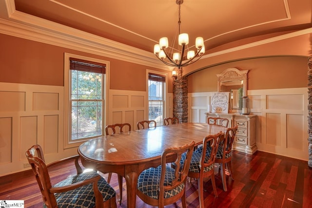 dining space with dark wood finished floors, an inviting chandelier, crown molding, a decorative wall, and a raised ceiling