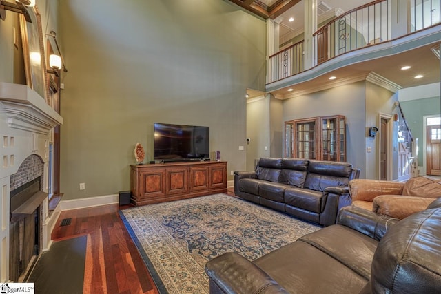 living area featuring baseboards, a high ceiling, a fireplace, dark wood-style flooring, and ornamental molding