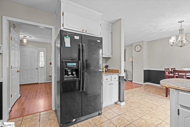 kitchen with a textured ceiling, an inviting chandelier, white cabinets, light tile patterned floors, and black refrigerator with ice dispenser