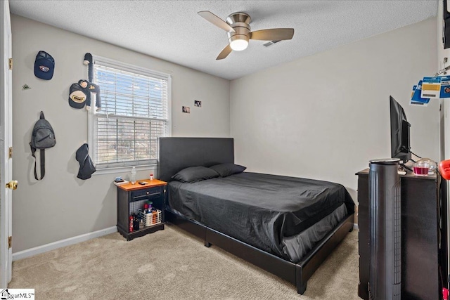 bedroom featuring a ceiling fan, baseboards, a textured ceiling, and carpet flooring