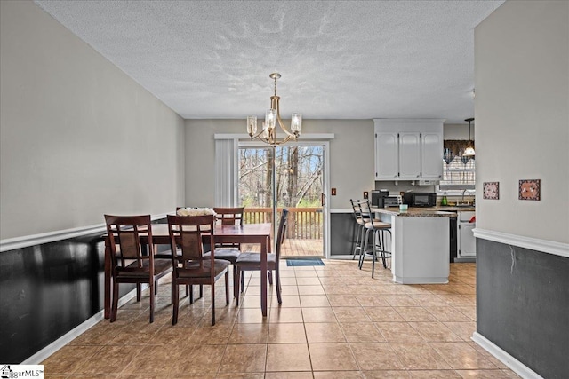 dining space with light tile patterned flooring, a notable chandelier, a textured ceiling, and baseboards