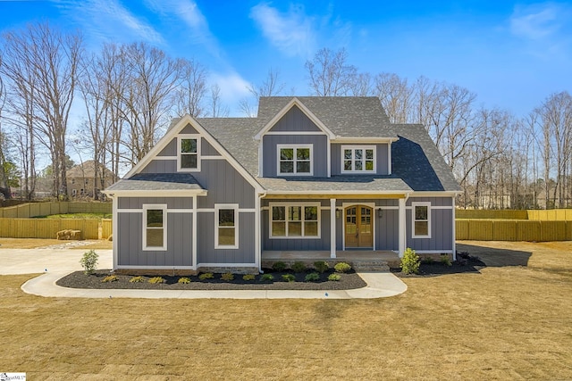 view of front facade with a front lawn, fence, board and batten siding, and french doors