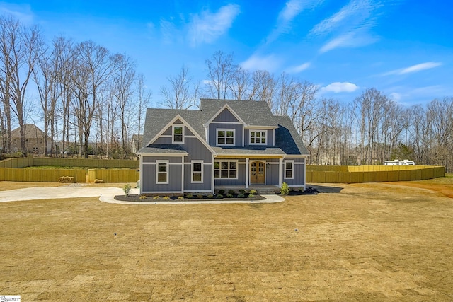 view of front of property with board and batten siding, a shingled roof, a front yard, and fence