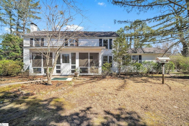 back of house with a sunroom and a chimney