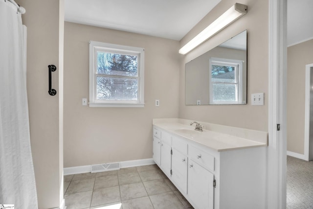 full bathroom with vanity, a healthy amount of sunlight, visible vents, and baseboards