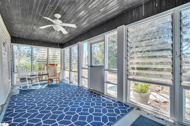 unfurnished sunroom with wooden ceiling, a ceiling fan, and a healthy amount of sunlight