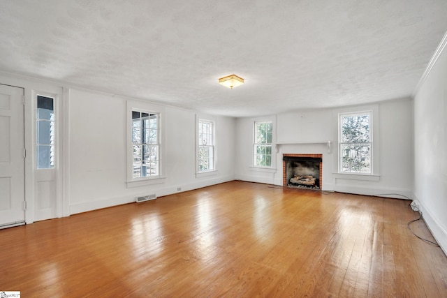 unfurnished living room with visible vents, hardwood / wood-style flooring, a textured ceiling, a fireplace, and baseboards