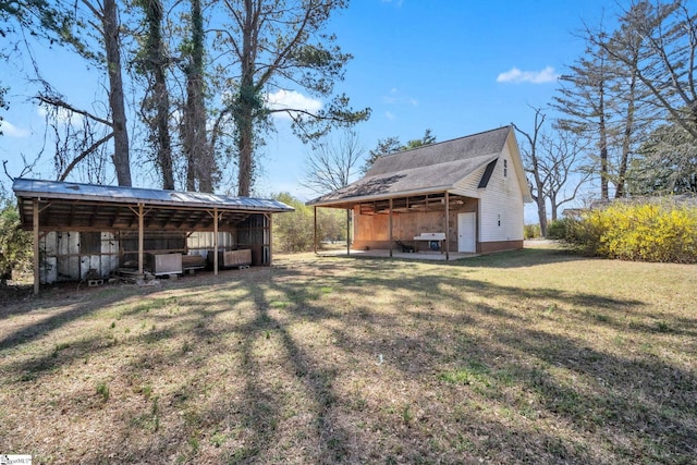 back of house with an outbuilding, a lawn, a detached carport, and an outdoor structure