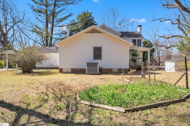 view of side of home featuring cooling unit, a vegetable garden, a yard, a chimney, and crawl space