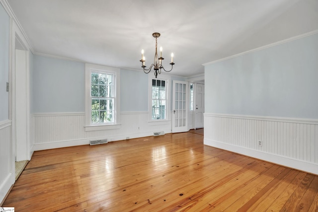 interior space with visible vents, hardwood / wood-style flooring, an inviting chandelier, crown molding, and wainscoting