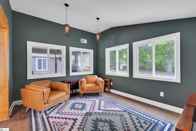 living area featuring visible vents, baseboards, lofted ceiling, and wood finished floors