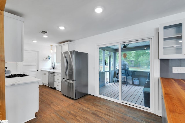 kitchen with appliances with stainless steel finishes, dark wood-style floors, white cabinets, wood counters, and a sink