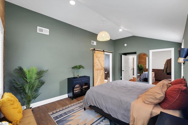 bedroom with wood finished floors, visible vents, baseboards, lofted ceiling, and a barn door