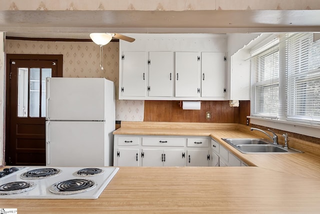 kitchen featuring a sink, freestanding refrigerator, stovetop, wallpapered walls, and light countertops