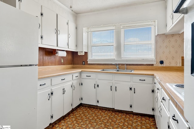 kitchen featuring white cabinetry, white appliances, tile patterned floors, and a sink