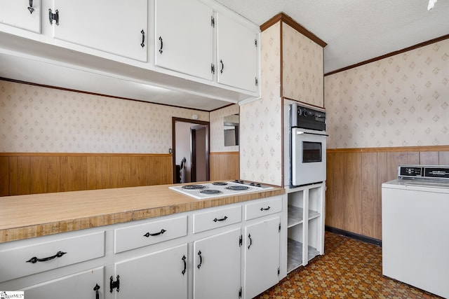 kitchen with washer / clothes dryer, white appliances, wainscoting, and wallpapered walls