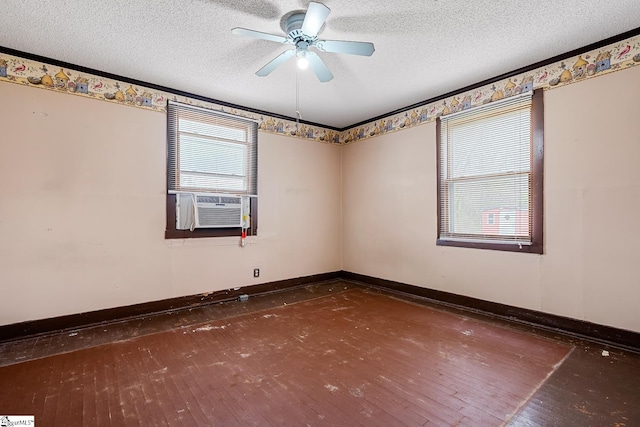 empty room featuring cooling unit, a textured ceiling, baseboards, and wood-type flooring