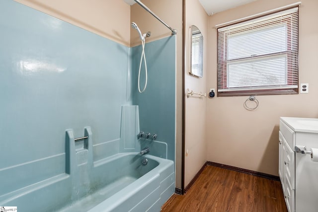 bathroom featuring baseboards, vanity, wood finished floors, and bathtub / shower combination