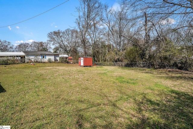 view of yard with fence, an outdoor structure, and a shed