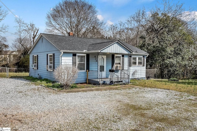 ranch-style home with a shingled roof, fence, a porch, cooling unit, and a chimney