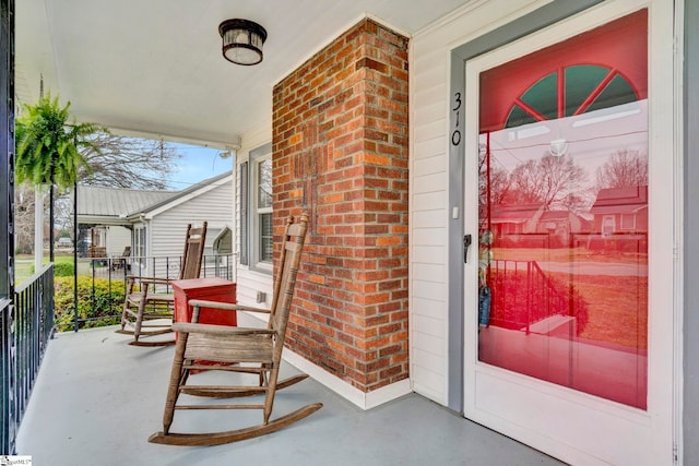 entrance to property featuring brick siding and covered porch