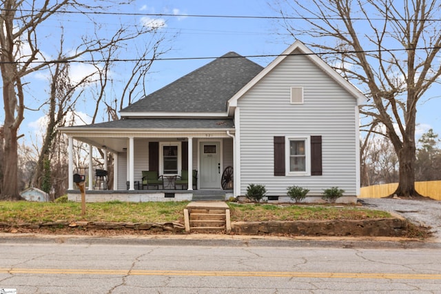 view of front of home with a porch, a shingled roof, and fence