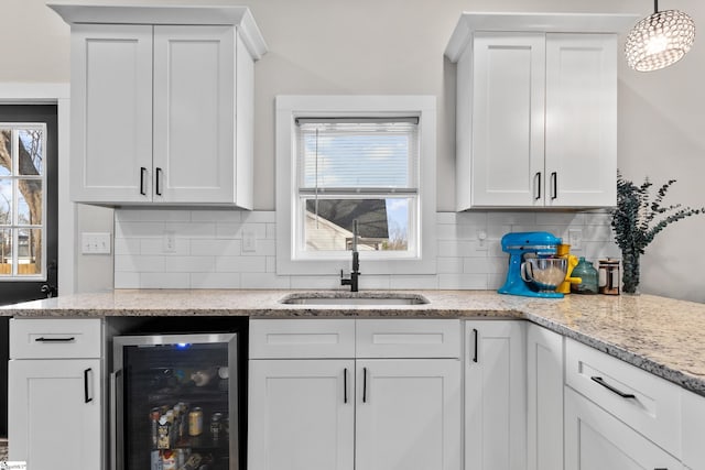 kitchen featuring beverage cooler, a healthy amount of sunlight, and white cabinetry