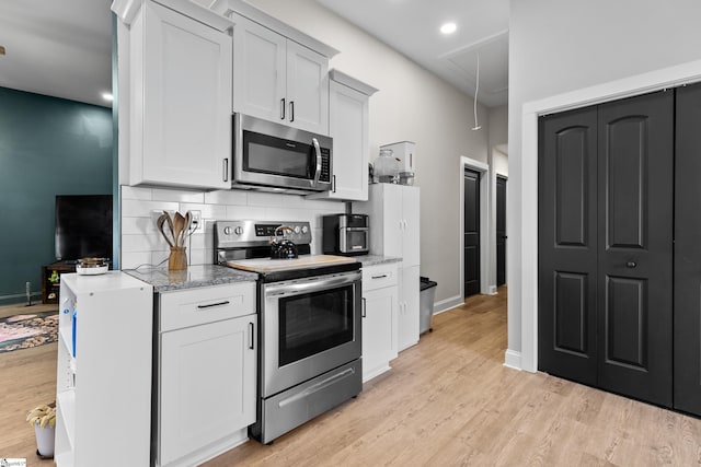 kitchen featuring light stone counters, baseboards, light wood-style flooring, stainless steel appliances, and tasteful backsplash