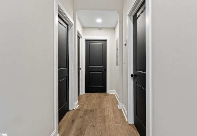 corridor with light wood finished floors and baseboards