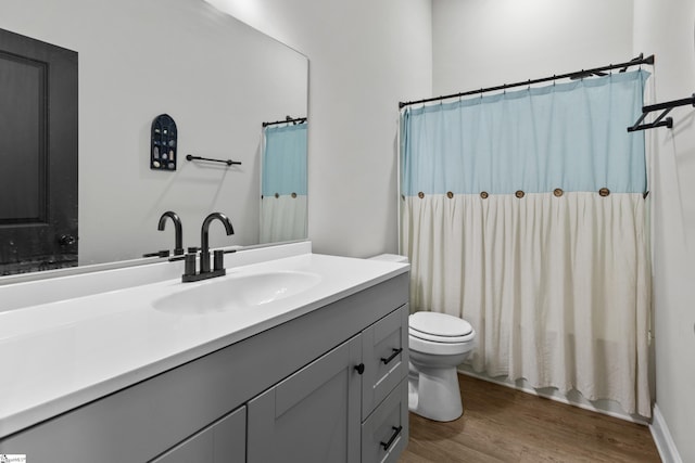 bathroom with a shower with shower curtain, toilet, vanity, and wood finished floors