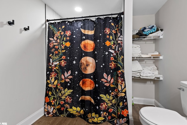 full bath featuring curtained shower, toilet, wood finished floors, and baseboards