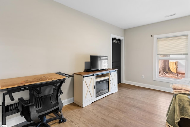 office with baseboards, visible vents, and light wood finished floors