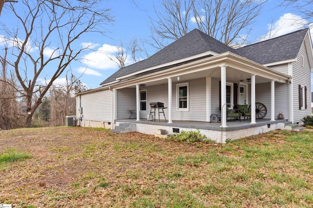 view of front of property with a front lawn, central AC unit, and roof with shingles