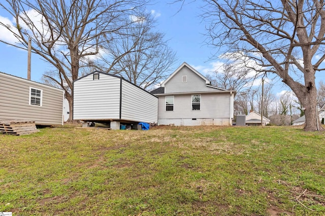 back of house with crawl space, a lawn, and an outdoor structure