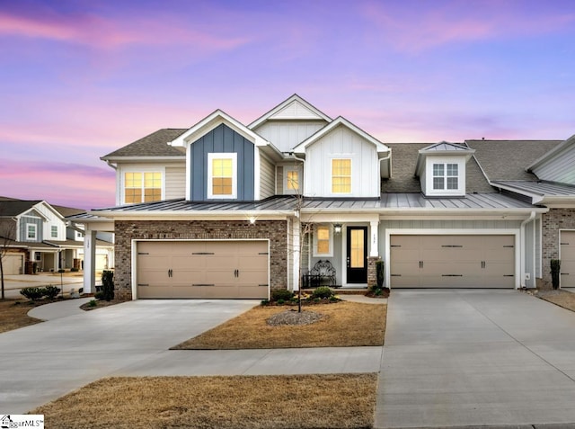 view of front of property with board and batten siding, brick siding, an attached garage, and driveway