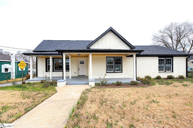 view of front facade with brick siding, board and batten siding, and covered porch