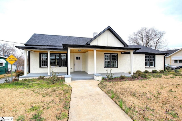 view of front of home with board and batten siding, brick siding, covered porch, and a shingled roof