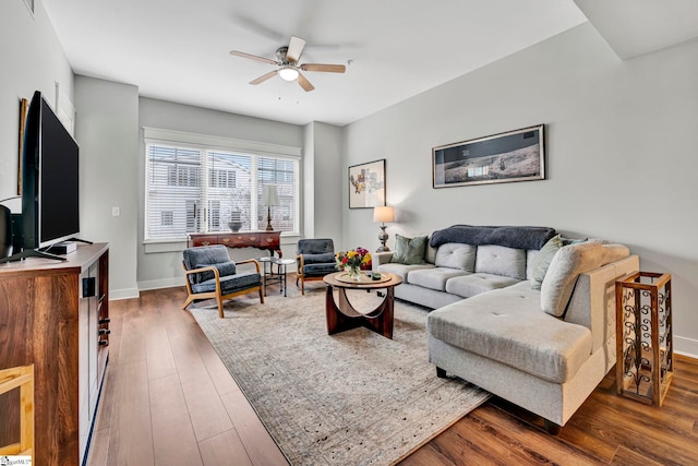 living area with baseboards, ceiling fan, and wood finished floors