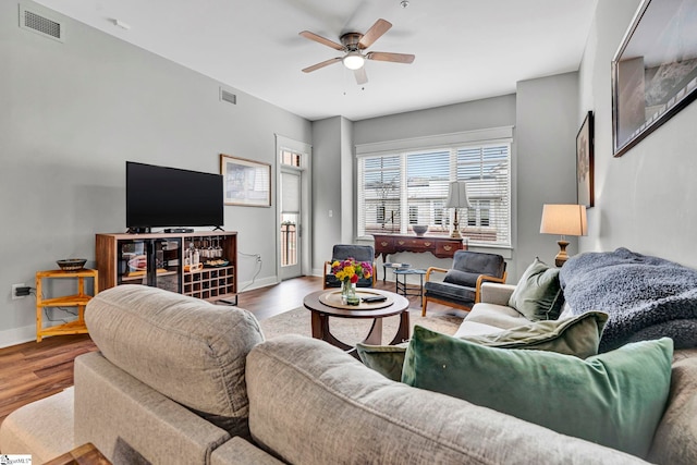 living area with a ceiling fan, wood finished floors, and visible vents