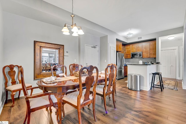 dining area with baseboards, wood finished floors, visible vents, and a chandelier