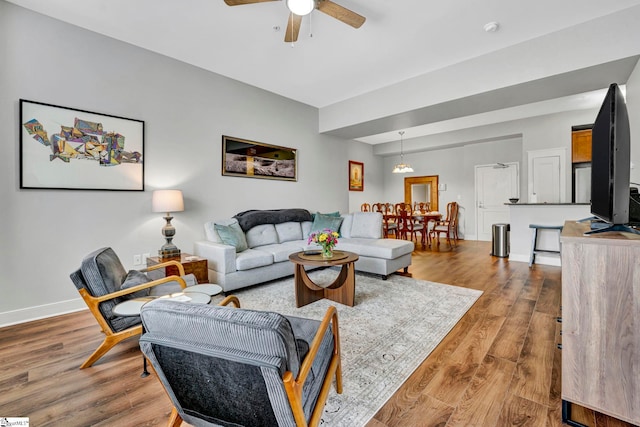 living room featuring ceiling fan, baseboards, and wood finished floors