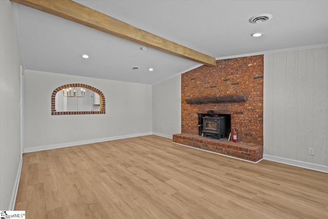 unfurnished living room featuring visible vents, a wood stove, a notable chandelier, wood finished floors, and vaulted ceiling with beams