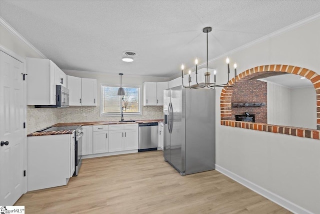 kitchen featuring visible vents, appliances with stainless steel finishes, white cabinetry, and crown molding