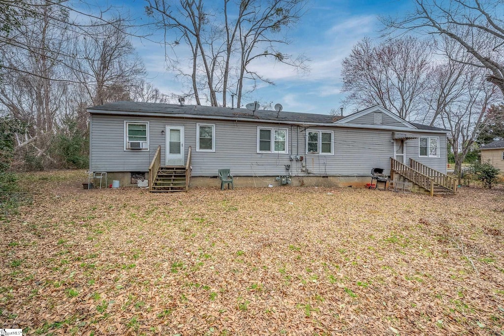 back of property featuring entry steps, a lawn, and crawl space