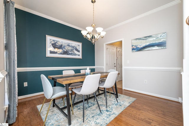 dining space featuring baseboards, wood finished floors, an inviting chandelier, and ornamental molding