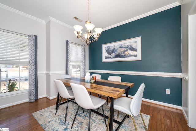 dining room featuring visible vents, wood finished floors, crown molding, baseboards, and a chandelier