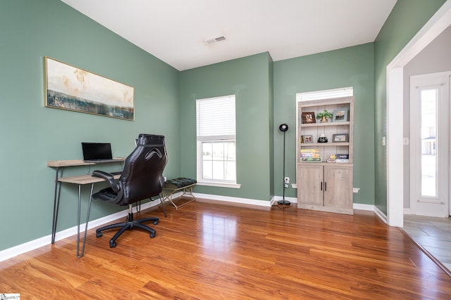 office space with wood finished floors, visible vents, and baseboards